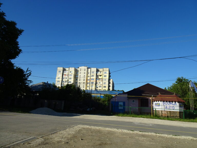 Straße, im Hintergrund ist ein älterer Wohnblock zu sehen